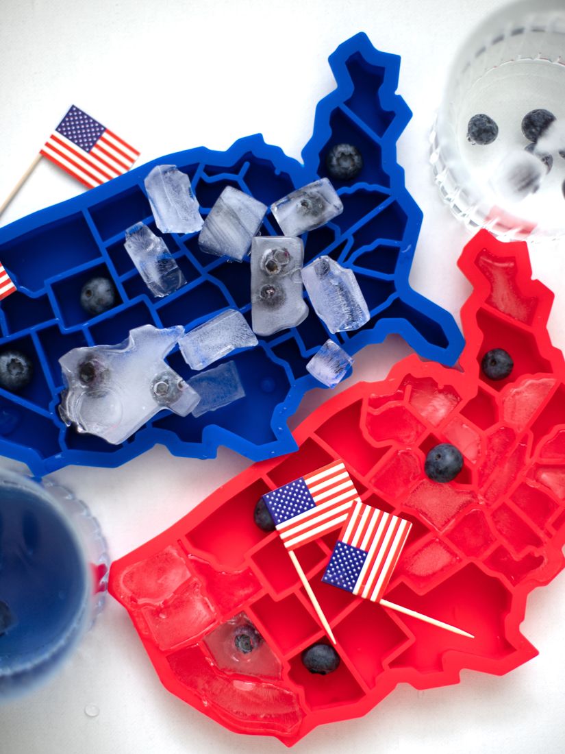 Trays filled with clear ice and blueberries next to drinks and a flag